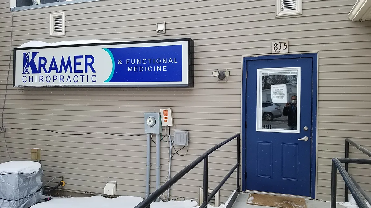 The blue back door at 815 Broadway St with the lit Kramer Chiropractic and Functional Medicine sign